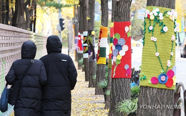 추위가 찾아온 17일 경기도 광명시의 한 거리에서 두꺼운 옷차림의 시민들이 뜨개옷 입은 가로수길을 걷고 있다. (사진=연합뉴스)